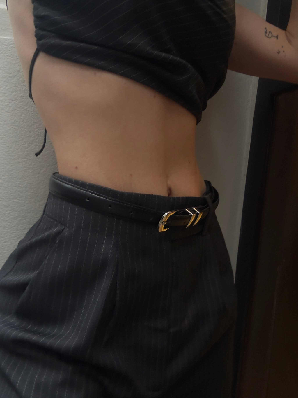 sleek black leather Celia Belt with silver chrome buckle worn with pinstripe pants