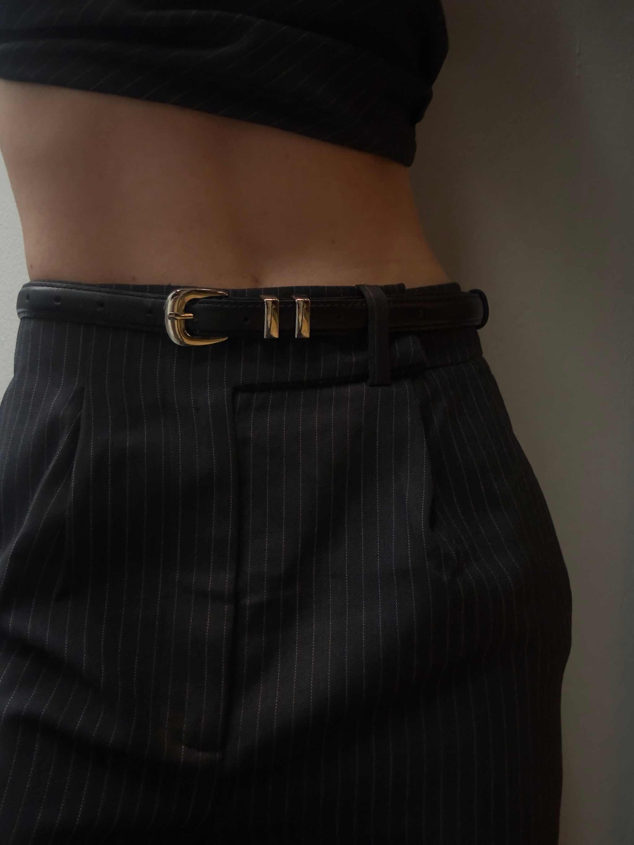 black leather belt with silver chrome buckle worn with pinstripe pants