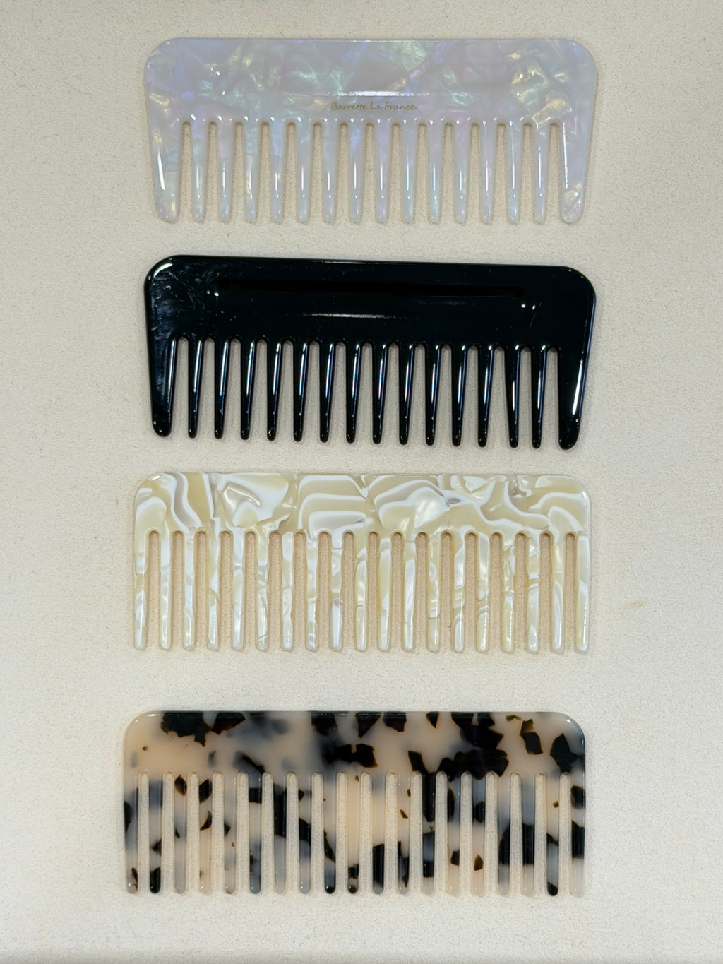 Four combs with different designs on a light beige background