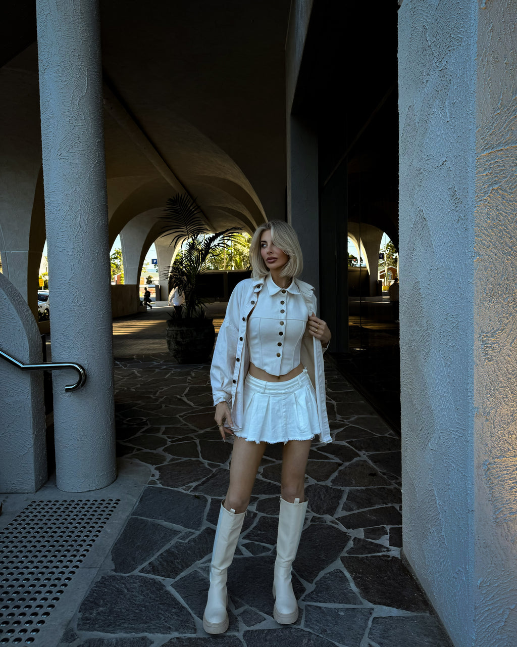 Ivory structured vest corset with panel detailing and brass buttons displayed inside Solana boutique.